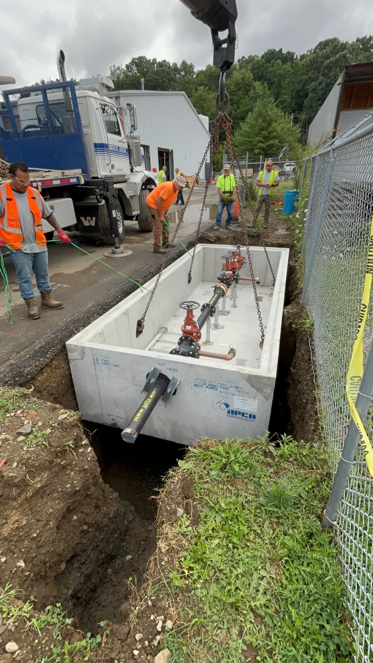 Astrada Services crew guiding a commercial water service vault into a prepared excavation